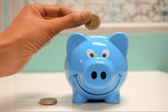 hand putting a coin in a piggy bank